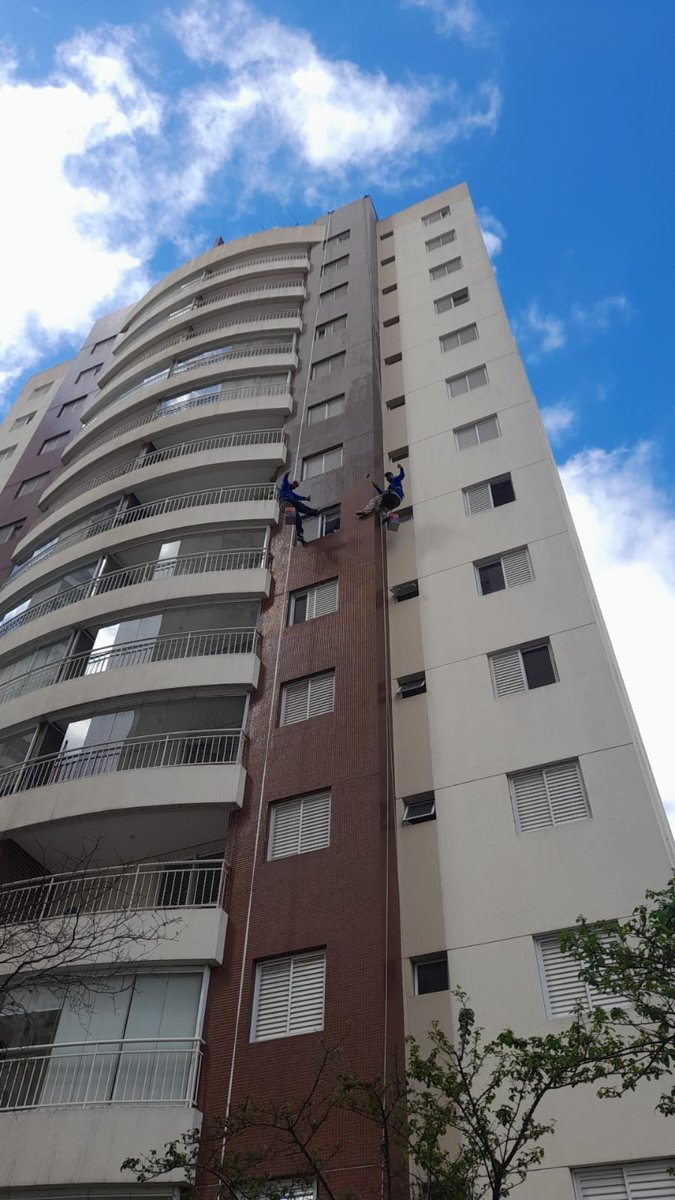 Profissionais suspensos em rapel finalizando acabamento de pastilhas prediais